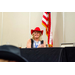  A woman wearing a red cowboy hat clapping while sitting at a table. 