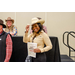  A woman tipping her cowboy hat in greeting towards the camera while holding a Best Dressed Winner Certificate. 