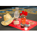   A center piece that is made up of a red bandana, an old oil lamp, a straw cowboy hat, a figurine of a cowboy boot, roses, a pile of rope, and a candle. 