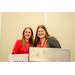  Two women posing behind a podium. 