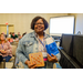  A woman holding a winning bingo card and a small blue gift bag with an envelope sticking out of it. 