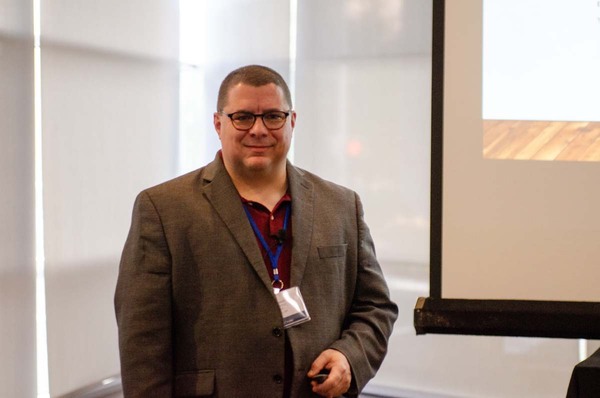 A gentleman standing next to a projection screen.