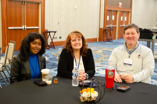 Two women sitting with a man around a table.