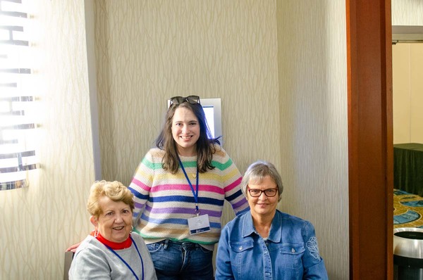 Katie Bibbee standing behind two women who are sitting down.